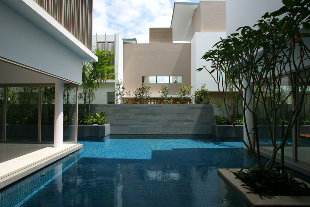 Diseño de piscina alargada actual a medida en patio con suelo de baldosas