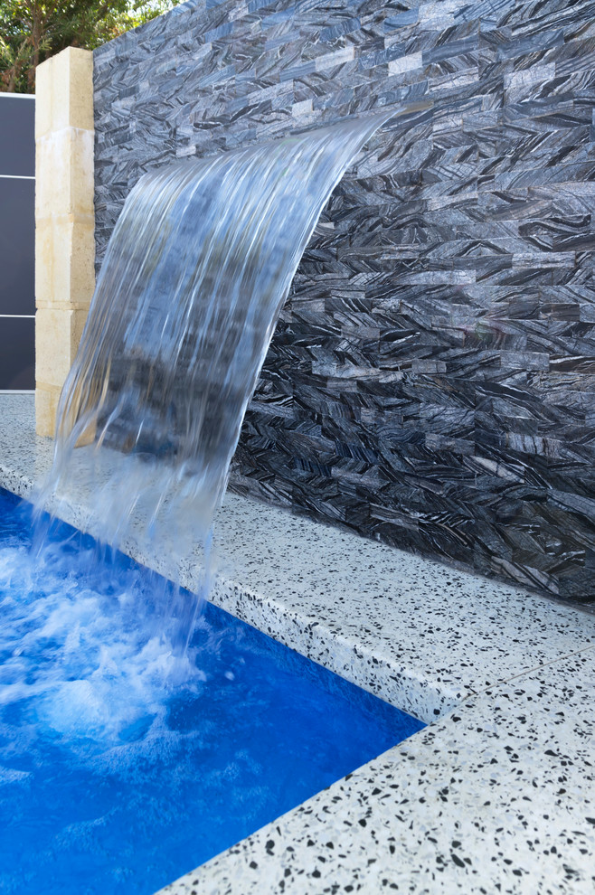 Esempio di una grande piscina monocorsia design personalizzata dietro casa con fontane e graniglia di granito