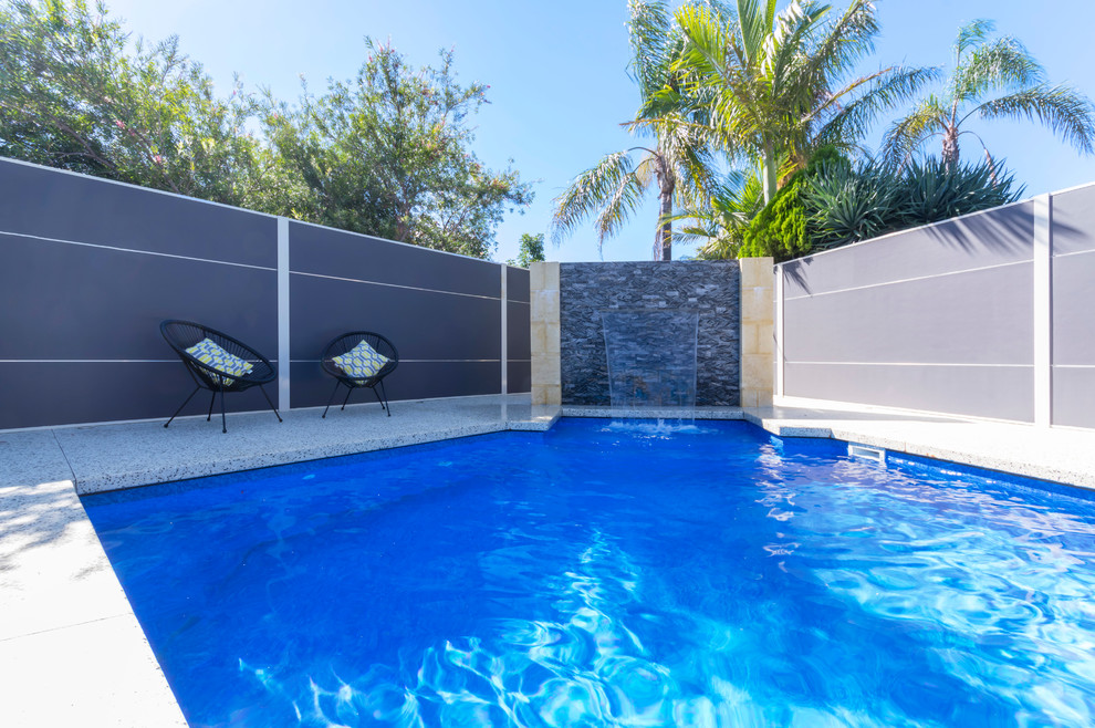 Modelo de piscina con fuente alargada actual grande a medida en patio trasero con granito descompuesto