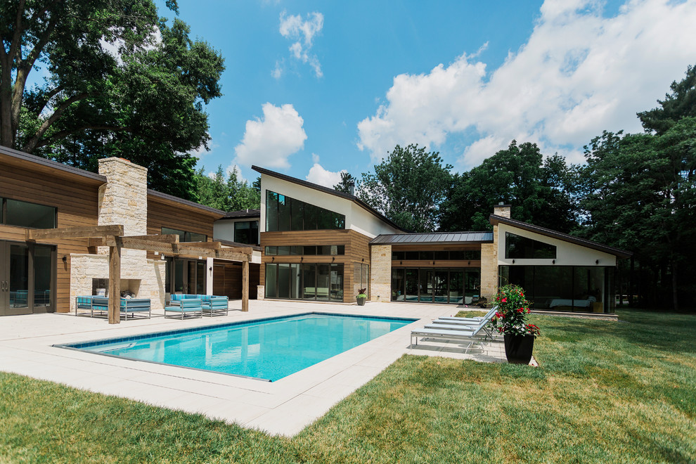 Diseño de piscina natural minimalista grande rectangular en patio trasero con adoquines de hormigón