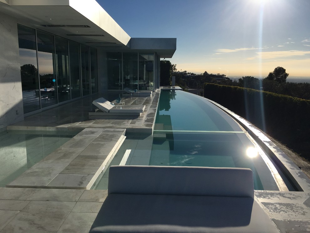 Esempio di un'ampia piscina a sfioro infinito moderna a "L" dietro casa con piastrelle