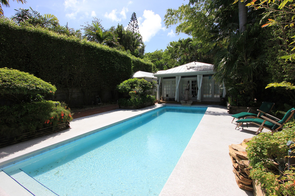 Diseño de casa de la piscina y piscina exótica grande rectangular en patio trasero con adoquines de hormigón