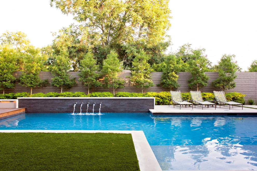 Moderner Pool hinter dem Haus in L-Form mit Wasserspiel in Dallas