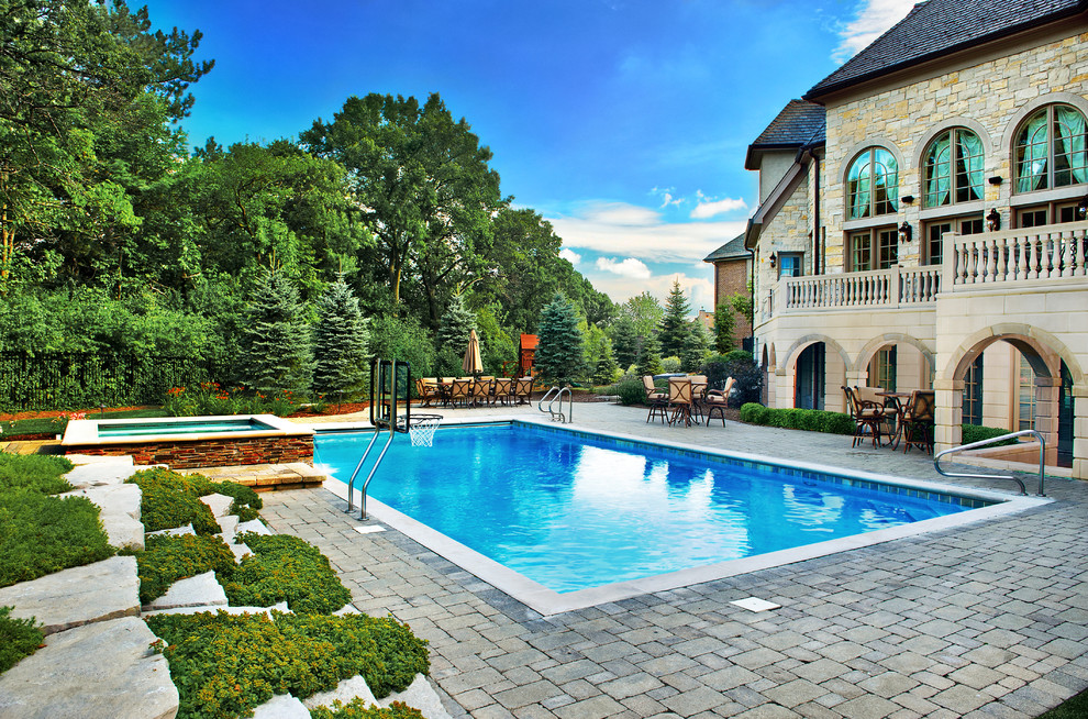 Esempio di una piscina monocorsia tradizionale rettangolare di medie dimensioni e dietro casa con pavimentazioni in cemento e una vasca idromassaggio
