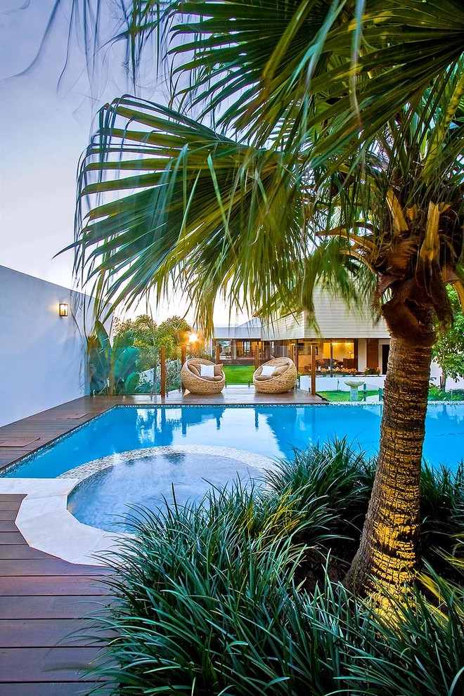 Pool house - mid-sized tropical backyard stone and custom-shaped infinity pool house idea in Brisbane