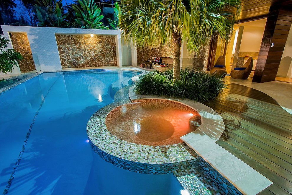 Imagen de casa de la piscina y piscina infinita tropical de tamaño medio a medida en patio trasero con adoquines de piedra natural