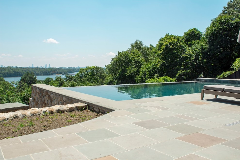 This is an example of a small modern back rectangular infinity swimming pool in Boston with decking.