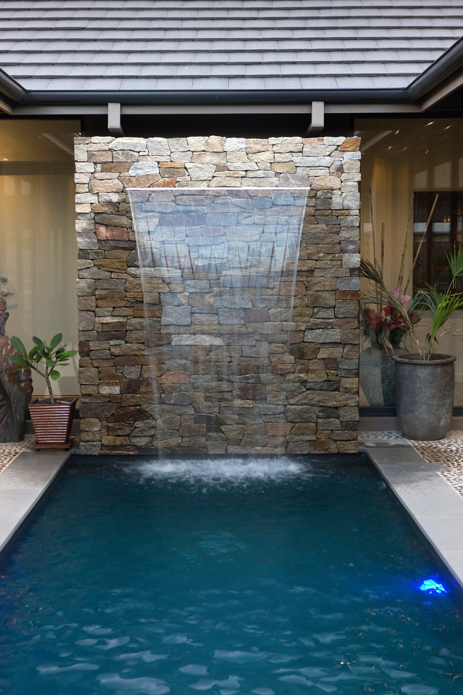 Cette image montre une piscine design de taille moyenne et rectangle avec un point d'eau, une cour et une terrasse en bois.