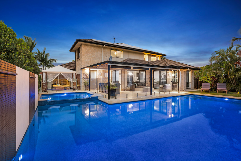 Cette image montre une grande piscine naturelle et arrière design sur mesure avec un bain bouillonnant et des pavés en pierre naturelle.