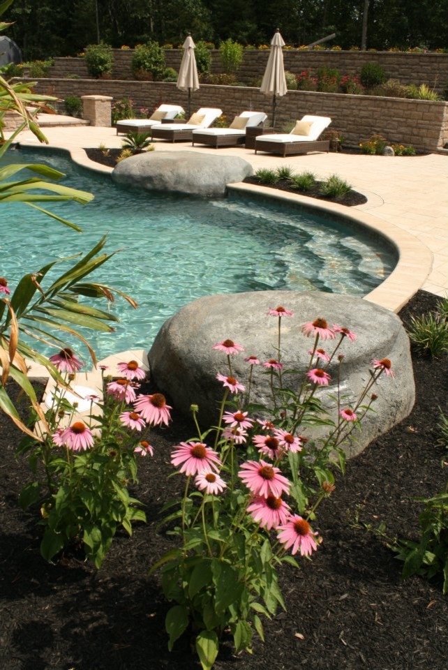 Imagen de piscina exótica grande tipo riñón en patio trasero con adoquines de hormigón