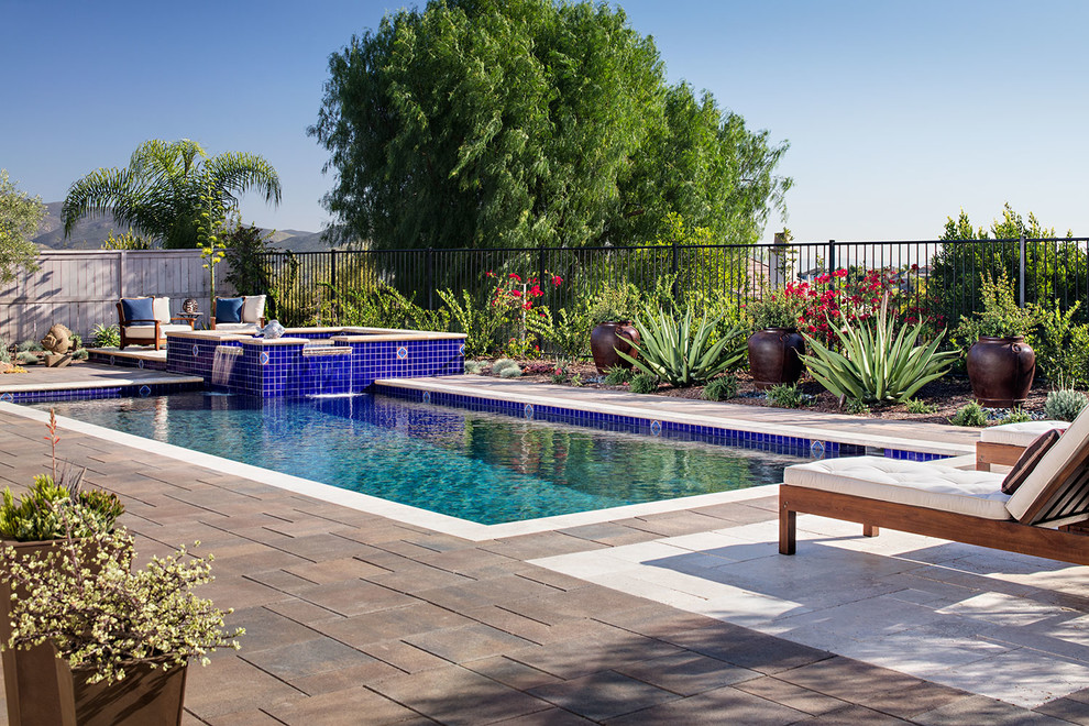 Exemple d'une piscine hors-sol et arrière méditerranéenne de taille moyenne et rectangle avec un bain bouillonnant et des pavés en pierre naturelle.
