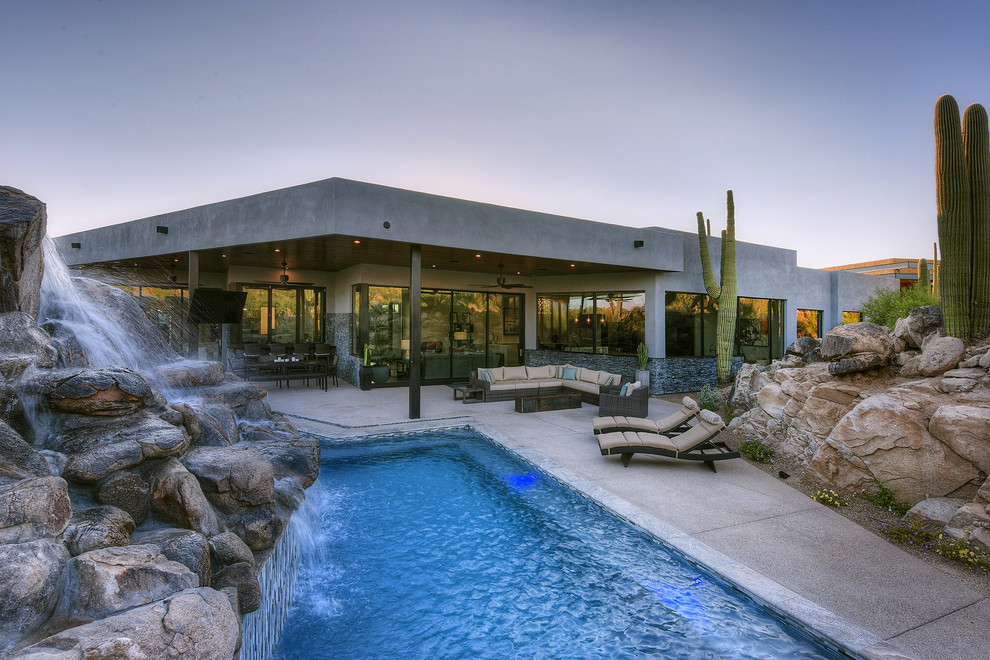 Foto de piscina infinita contemporánea rectangular en patio trasero con losas de hormigón