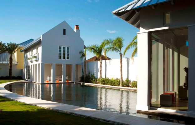 Foto di una grande piscina a sfioro infinito tropicale personalizzata dietro casa con una dépendance a bordo piscina e pavimentazioni in cemento