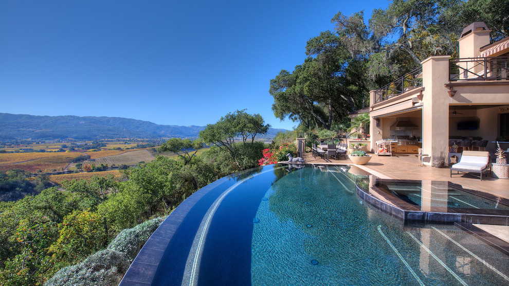Idee per un'ampia piscina a sfioro infinito mediterranea personalizzata dietro casa con fontane e pavimentazioni in cemento