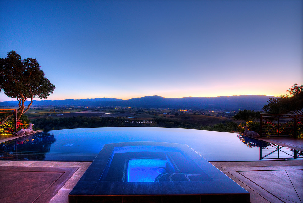 Foto di un'ampia piscina a sfioro infinito mediterranea personalizzata in cortile con fontane e cemento stampato