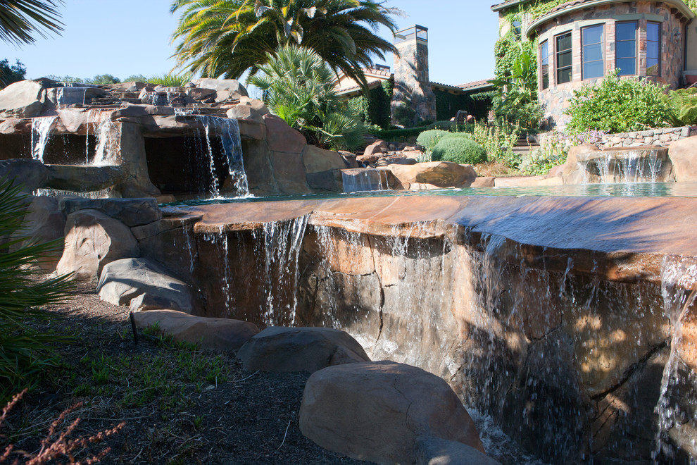 Ispirazione per una grande piscina naturale mediterranea personalizzata dietro casa con fontane e pavimentazioni in pietra naturale
