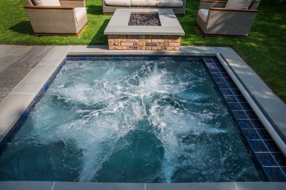 Exempel på en liten klassisk rektangulär pool på baksidan av huset, med spabad och naturstensplattor