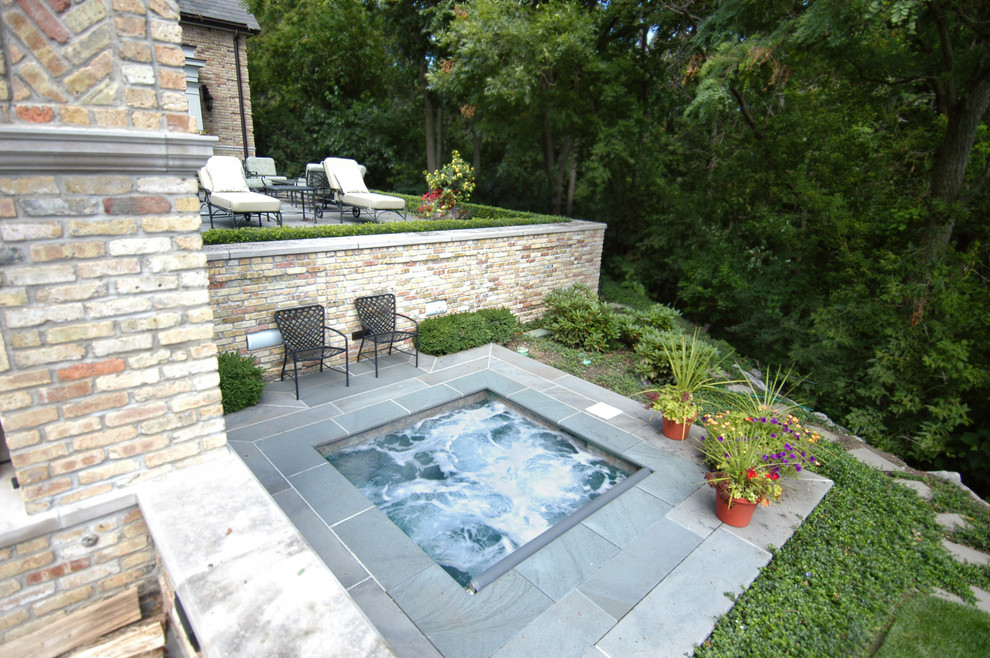 Aménagement d'une petite piscine arrière classique rectangle avec un bain bouillonnant et des pavés en pierre naturelle.