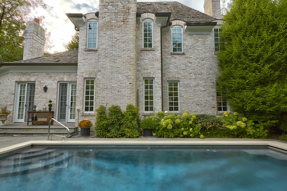 Foto de piscina alargada tradicional pequeña rectangular en patio lateral con adoquines de piedra natural