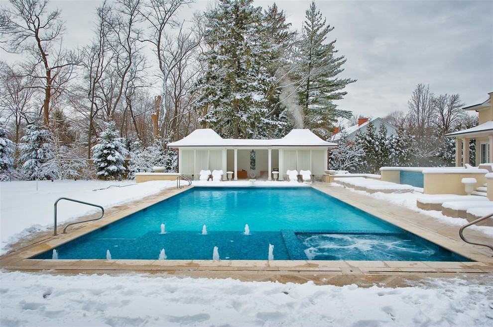 Esempio di una piscina monocorsia tradizionale rettangolare di medie dimensioni e dietro casa con pavimentazioni in pietra naturale e una vasca idromassaggio