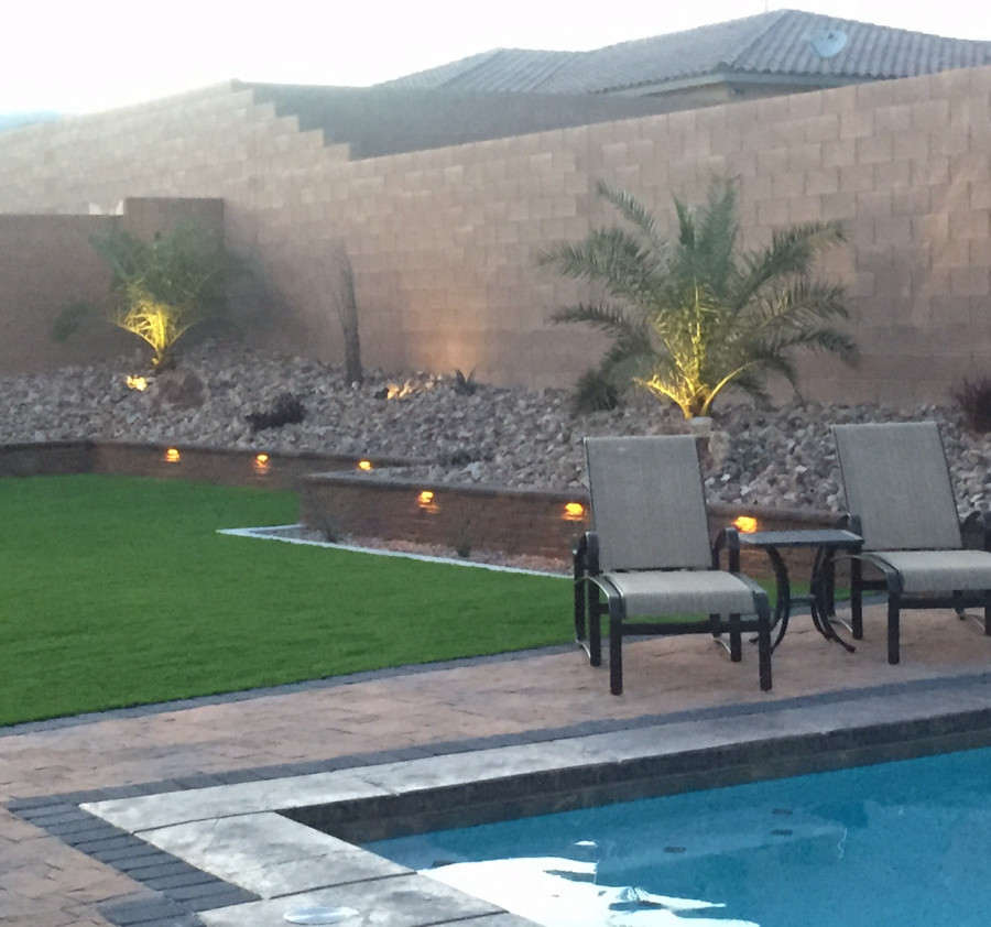 Modelo de piscina alargada tradicional de tamaño medio rectangular en patio trasero con adoquines de ladrillo