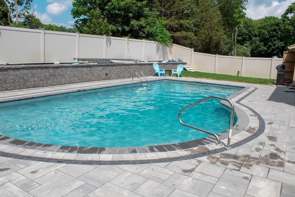 Design ideas for a small classic back custom shaped natural swimming pool in Boston with natural stone paving.