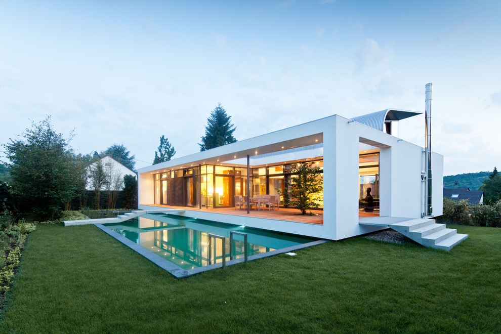 Imagen de piscina alargada actual grande rectangular en patio lateral con losas de hormigón