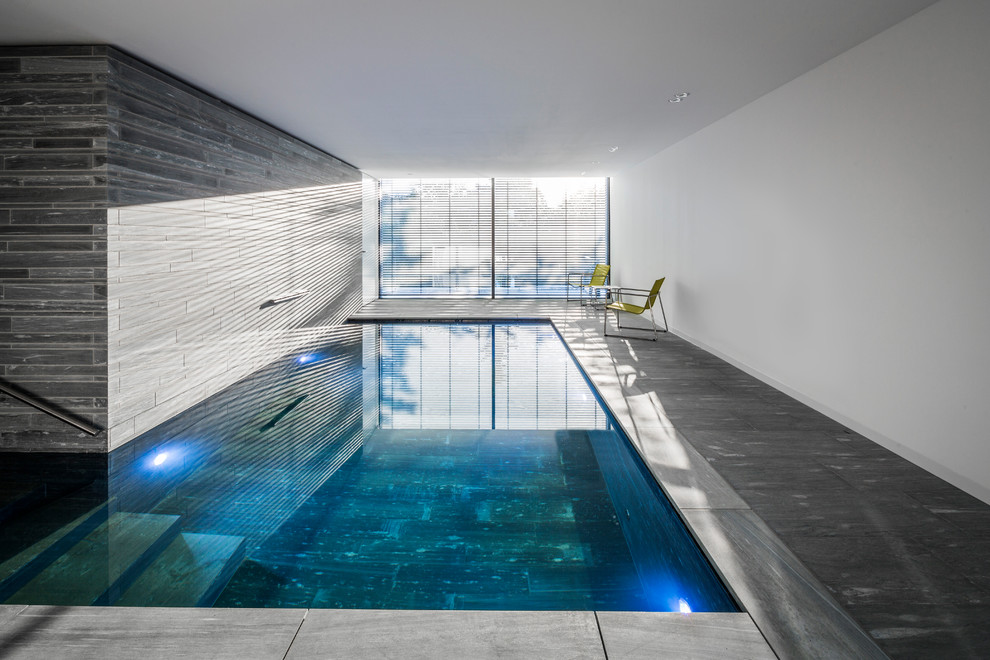 Esempio di una grande piscina coperta monocorsia moderna a "L" con pavimentazioni in pietra naturale