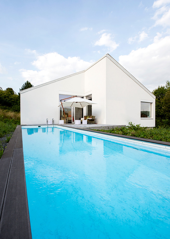 Modelo de piscina alargada actual grande rectangular en patio trasero con entablado