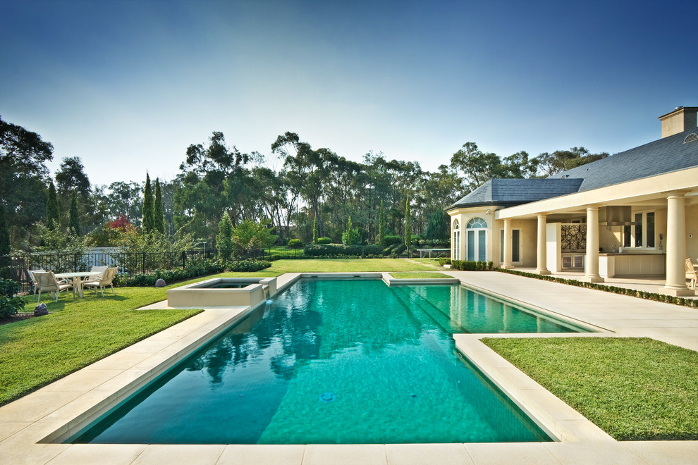 Exempel på en klassisk anpassad pool på baksidan av huset, med marksten i betong