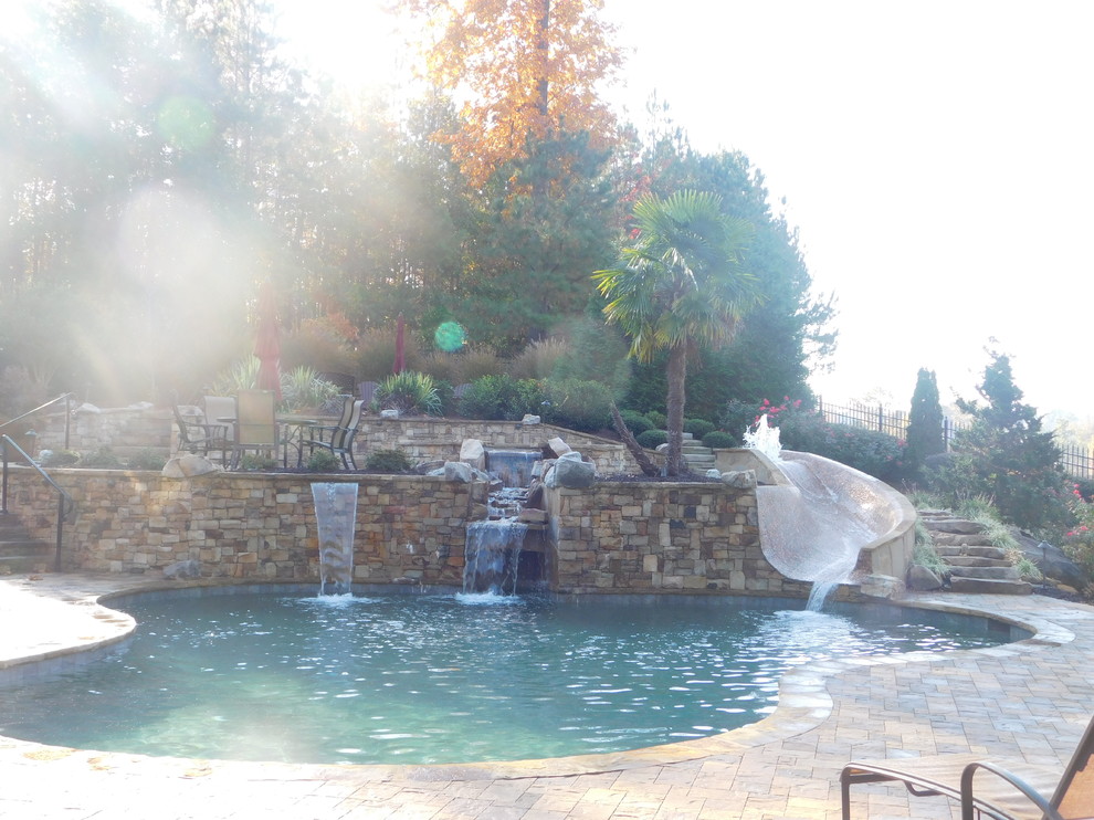 Idee per una grande piscina stile rurale personalizzata dietro casa con un acquascivolo e pavimentazioni in pietra naturale