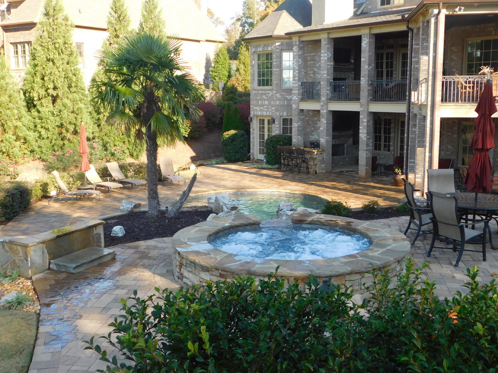 Immagine di una grande piscina stile rurale personalizzata dietro casa con un acquascivolo e pavimentazioni in pietra naturale