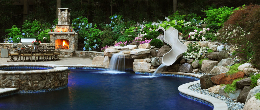 Ejemplo de piscina con tobogán alargada clásica grande a medida en patio trasero con gravilla