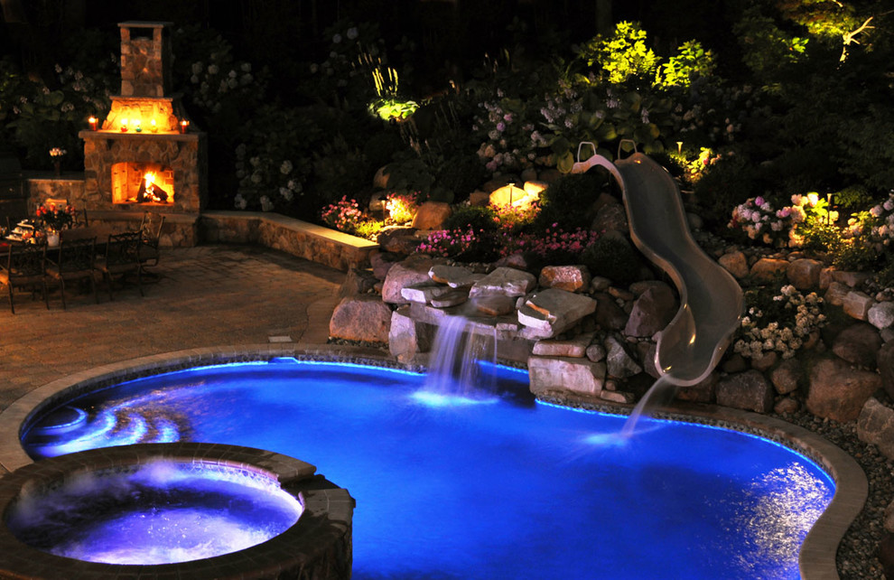 Modelo de piscina con tobogán alargada tradicional grande a medida en patio trasero