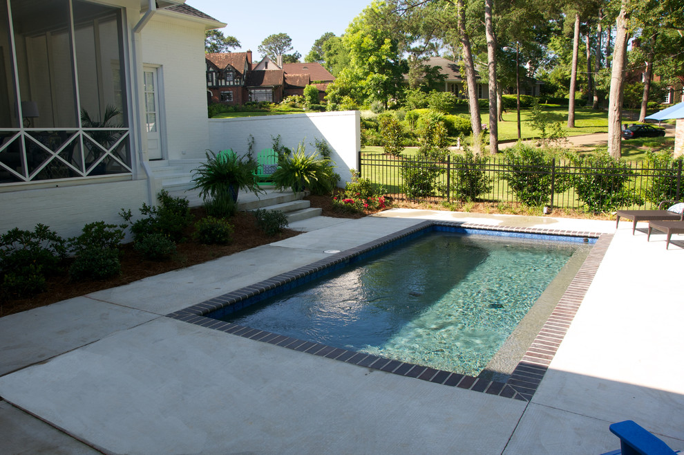 Imagen de piscina tradicional grande rectangular en patio trasero con losas de hormigón
