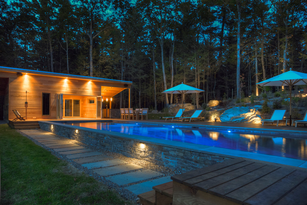 Imagen de casa de la piscina y piscina alargada moderna de tamaño medio rectangular en patio lateral con entablado