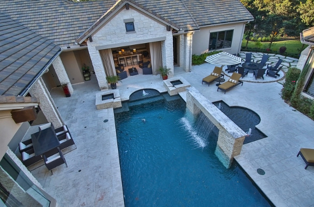 Inspiration for a large traditional back rectangular lengths swimming pool in Houston with a water feature and natural stone paving.
