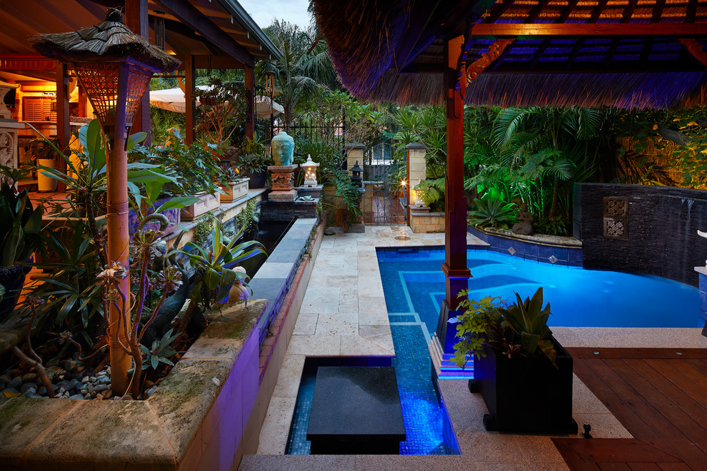 Immagine di una piccola piscina tropicale personalizzata dietro casa con fontane e pedane