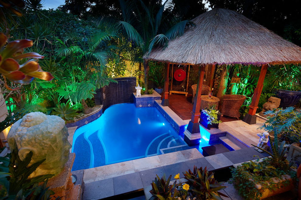 Modelo de piscina con fuente exótica pequeña a medida en patio trasero con adoquines de hormigón
