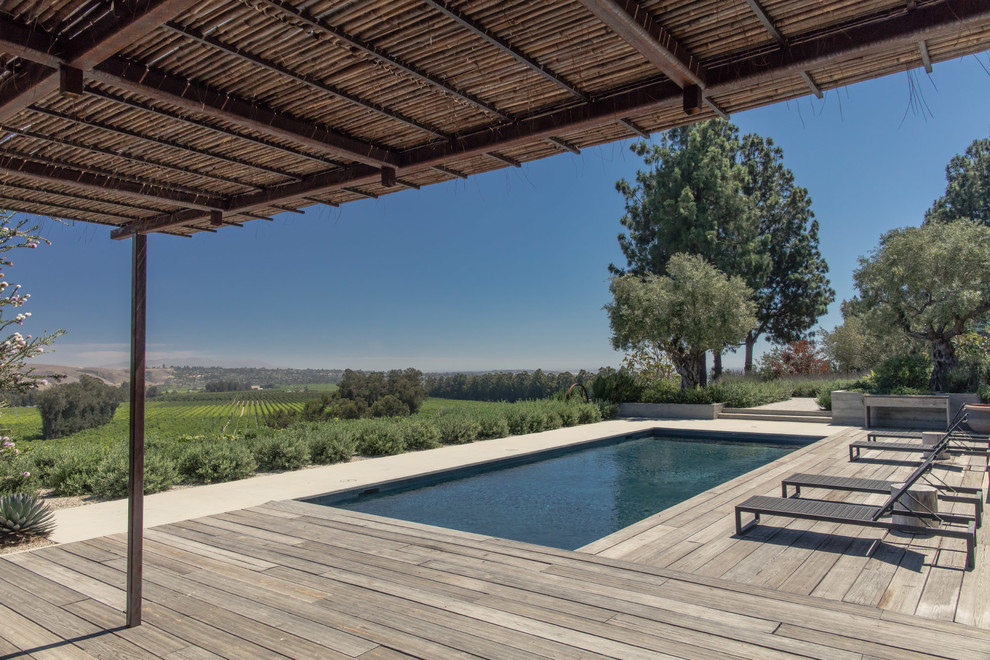 Foto de casa de la piscina y piscina contemporánea rectangular en patio trasero con entablado
