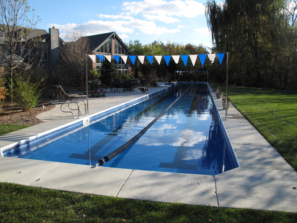 Photo of an expansive traditional back l-shaped lengths swimming pool in Chicago with concrete slabs.