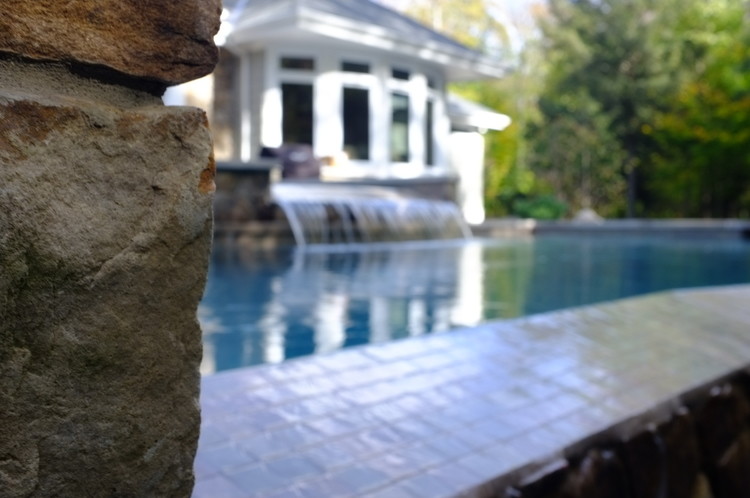 Idee per una grande piscina a sfioro infinito minimal personalizzata dietro casa con una vasca idromassaggio e pavimentazioni in pietra naturale