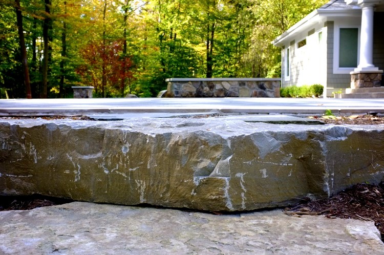 Design ideas for a large contemporary back custom shaped infinity hot tub in Grand Rapids with natural stone paving.