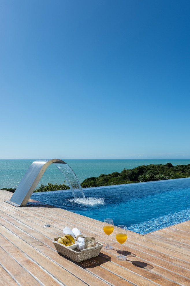 Стильный дизайн: прямоугольный бассейн-инфинити на заднем дворе в морском стиле с фонтаном и настилом - последний тренд