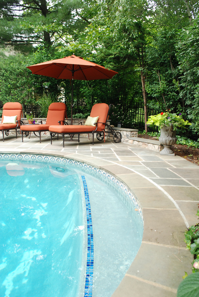 Photo of a medium sized classic back kidney-shaped natural swimming pool in Philadelphia with a pool house and natural stone paving.