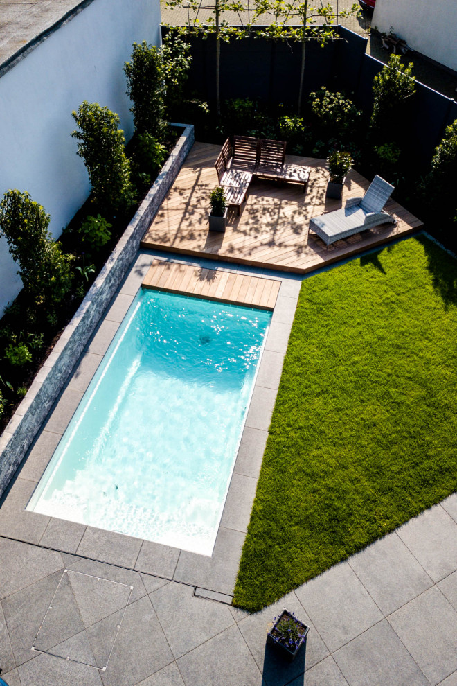 Réalisation d'une piscine latérale design de taille moyenne et rectangle avec des pavés en pierre naturelle.
