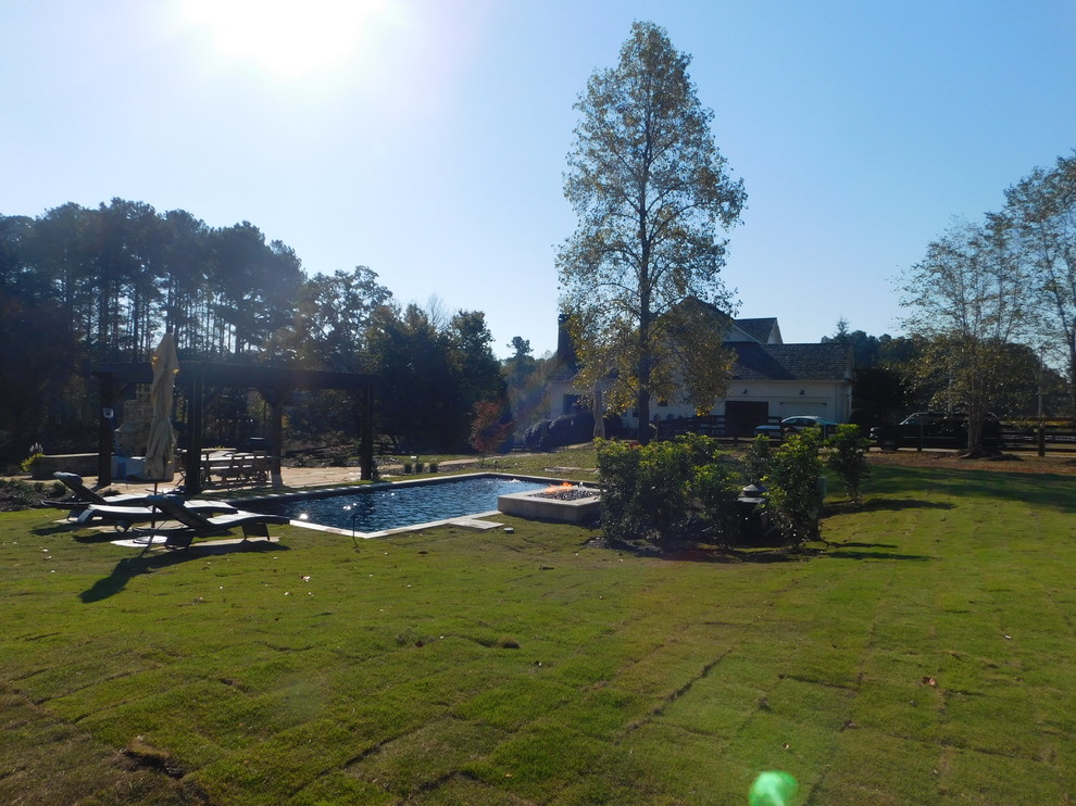 Photo of a medium sized mediterranean back rectangular swimming pool in Atlanta with a water feature and natural stone paving.