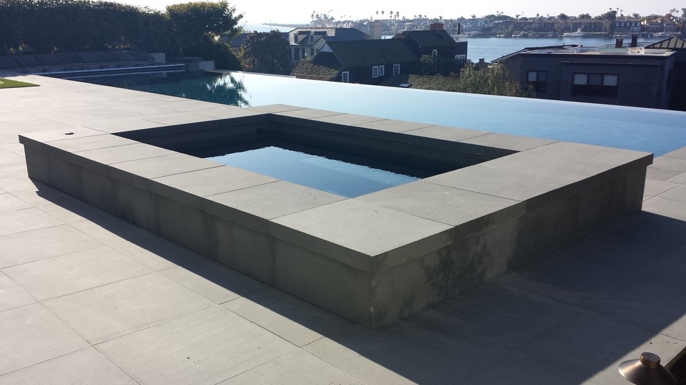 Свежая идея для дизайна: большой бассейн-инфинити произвольной формы на заднем дворе в современном стиле с фонтаном и покрытием из каменной брусчатки - отличное фото интерьера