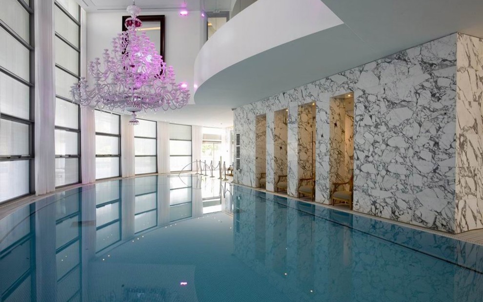 Idee per una grande piscina coperta a sfioro infinito design personalizzata con piastrelle