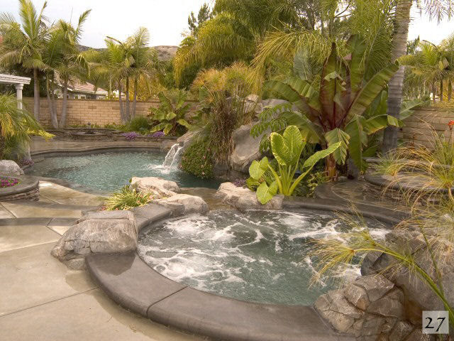 Diseño de piscina con fuente natural de estilo americano grande a medida en patio trasero con losas de hormigón